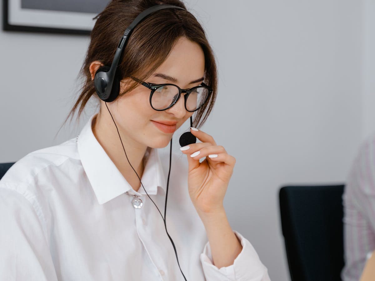 A smiling support agent in a headset speaking into the microphone